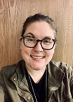 Woman with brown hair pulled back into a ponytail wearing designer rimmed glasses and a green shirt